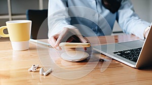 Working Woman putting smartphone on wireless charger in office