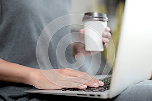 Working woman sitting. She is working with a notebook and is drinking coffee.