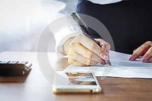 Working woman writing on paper at office with mobile phone photo