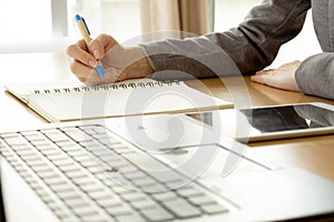 Working woman writing on paper and typing on laptop com
