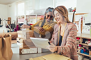 Working women at their store. They accepting new orders online and packing merchandise for customer