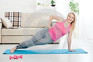 Working with your body. Full length of beautiful middle aged woman in sportswear doing plank while standing in front of