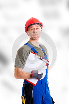 Workman in blue dungarees with clipboard looking sceptical