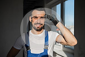 Workman in blue overalls and goggles smiling