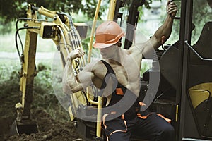 Workman concept. Workman flex biceps and triceps muscle. Strong workman at excavator cabin. Workman in working uniform