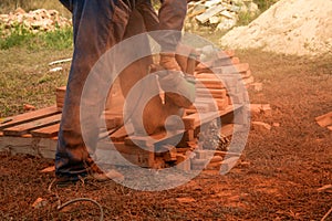 Workman cutting orange bricks with a radial saw
