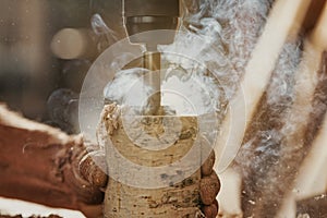 Workman drilling into a section of a wooden branch