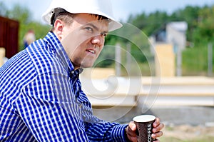 Workman drinking coffee in his hardhat