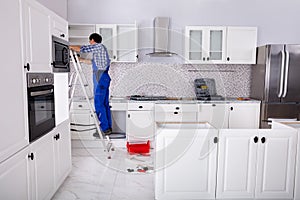 Workman Fixes A Hinge To A Kitchen Cabinet