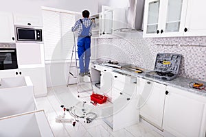 Workman Fixes A Hinge To A Kitchen Cabinet