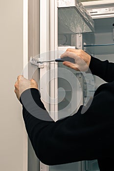 Workman fixes a kitchen facade on the door of the built-in refrigerator.