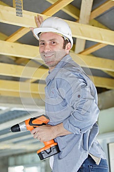 workman fixing roof beam with cordless drill