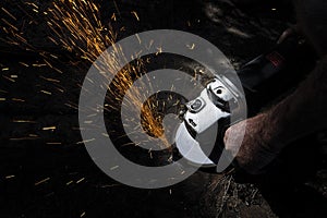 Workman grinding steel with sparks flying.