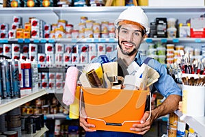 Workman holding basket with picked tools in paint store