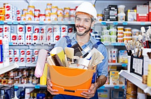 Workman holding basket with picked tools in paint store