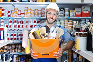 Workman holding basket with picked tools in paint store