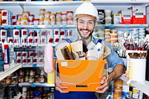 Workman holding basket with picked tools in paint store