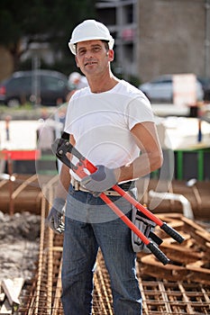workman holding metal pliers tool at site