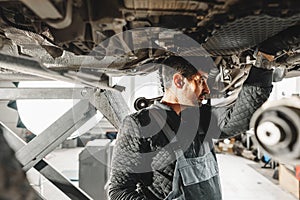 Workman mechanic working under car in auto repair shop