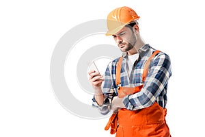 workman in orange overall and hard hat using smartphone