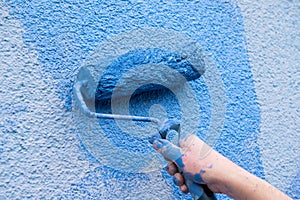 Workman painting the wall in blue