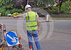 Workman pointing down toward road works