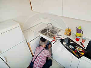 Workman repair pipes on sink in the kitchen