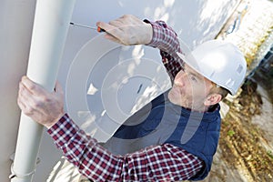 Workman replacing guttering on exterior house