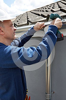 Workman Replacing Guttering On Exterior Of House