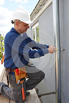 Workman Replacing Guttering On Exterior Of House