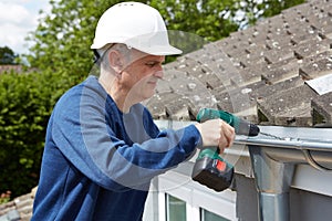 Workman Replacing Guttering On Exterior Of House photo