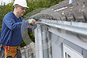 Workman Replacing Guttering On Exterior Of House