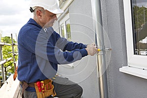 Workman Replacing Guttering On Exterior Of House photo