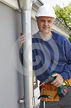 Workman Replacing Guttering On Exterior Of House