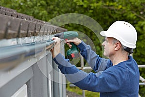 Workman Replacing Guttering On Exterior Of House photo