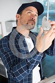 workman replacing lightbulb in suspended lamp