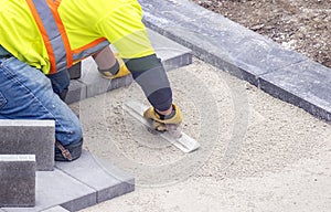 Workman in safety jacket preparing the foundation of patio pavers