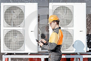 Workman servicing air conditioning or heat pump with digital tablet
