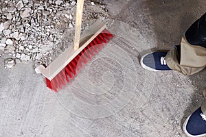 Workman sweeping the rubble on the floor with a broom