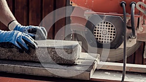 Workman using an angle grinder to cut a concrete block in a side