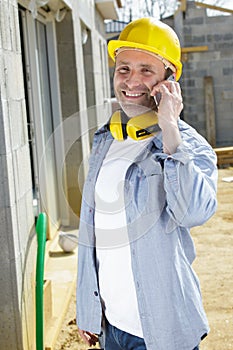 workman using smartphone outside property