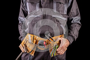 Workman in work clothes and tool belt. Production worker with a drill in his hand