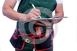 Workman writing in diary isolated on white. Man wearing coverall and tool belt