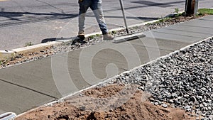 Workmen finish and smooth concrete surface on new cement sidewal