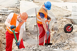 Workmen pouring sand into barrow