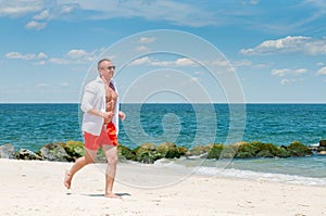 Workout. Athletic man running on beach.