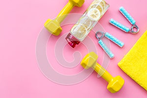 Workout with bars, bottle of water and wrist builder pink background top view mockup