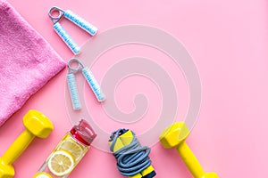 Workout with bars, bottle of water and wrist builder pink background top view mockup