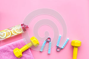 Workout with bars, bottle of water and wrist builder pink background top view mockup