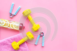 Workout with bars, bottle of water and wrist builder pink background top view mockup